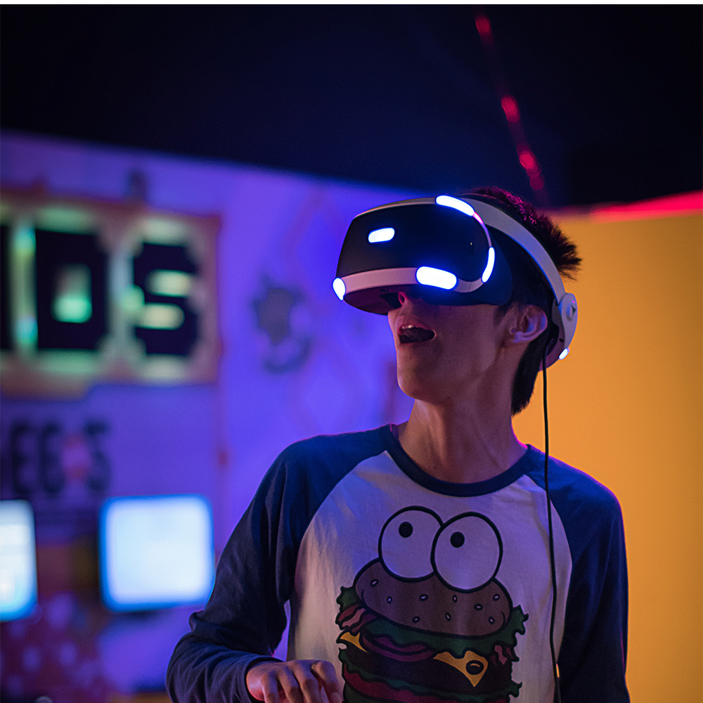 young man in dark room surrounded by neon lights and wearing a VR headset