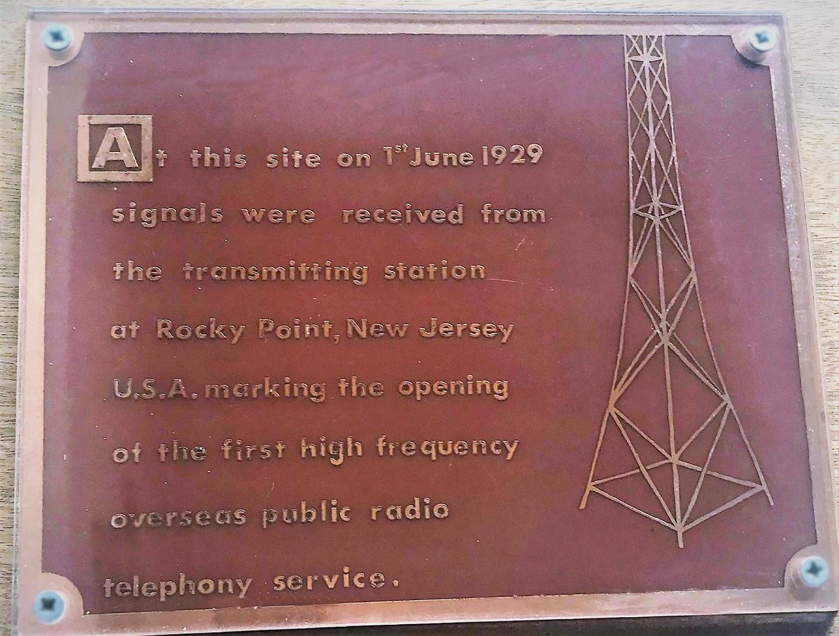 The plaque reads: "At the site on 1 June 1929 signals were received from the transmitting station at Rocky Point, New Jersey U.S.A. marking the opening of the first high frequency overseas public radio telephony service.