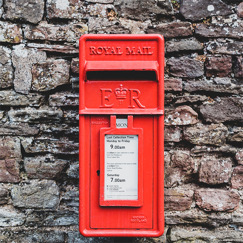 red post box against a grey stone wall