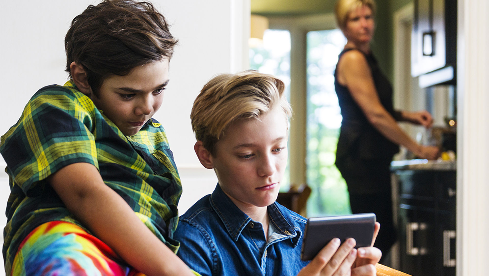 Two children looking at a phone or tablet together.