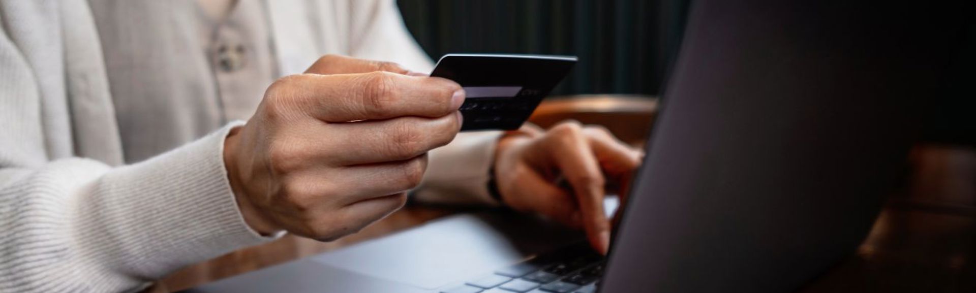 Woman holding card and laptop (1336 × 560px)