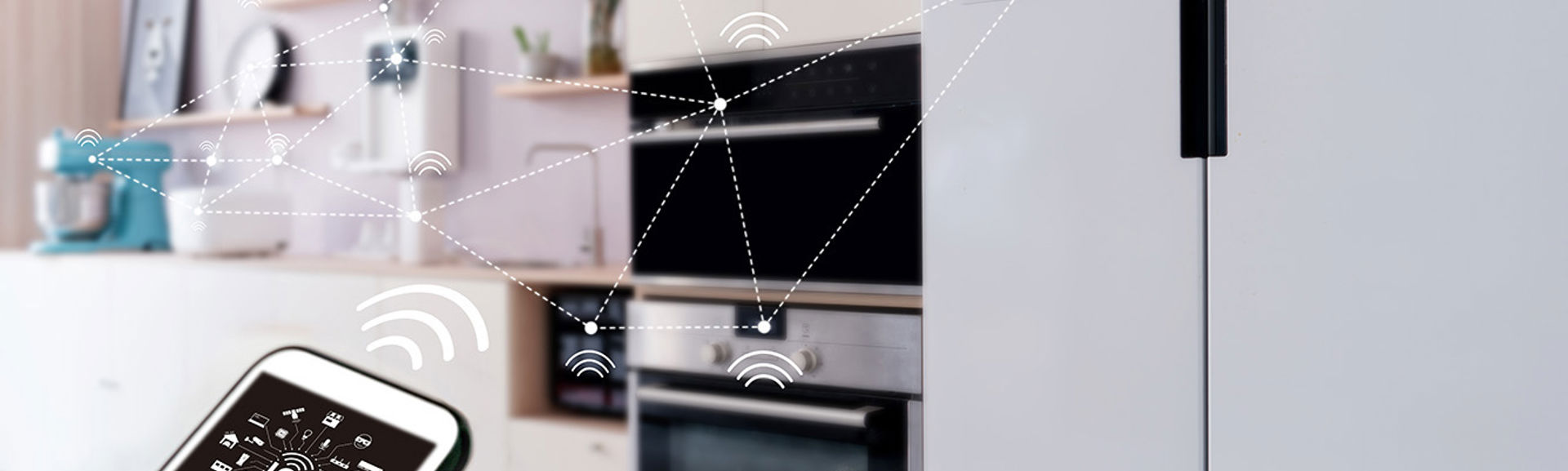 A smartphone with an app on screen that is connecting to various appliances in a modern kitchen