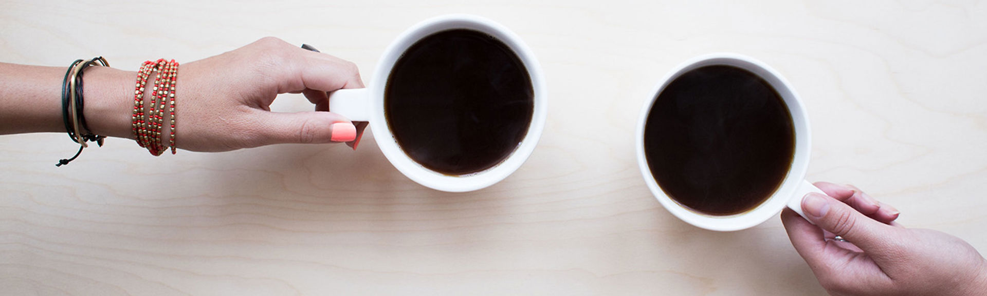 Two hands holding coffee cups