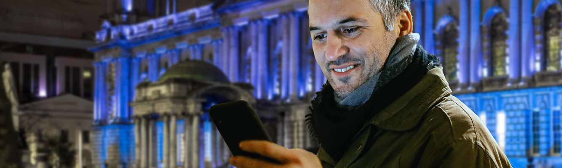 A man using a mobile phone in front of the City Hall in Belfast