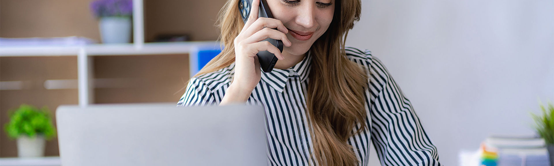 Woman on her mobile phone while sitting at a desk