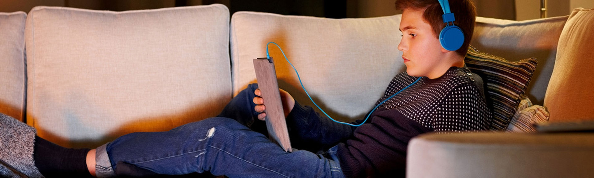 A boy listening to music while using a tablet device