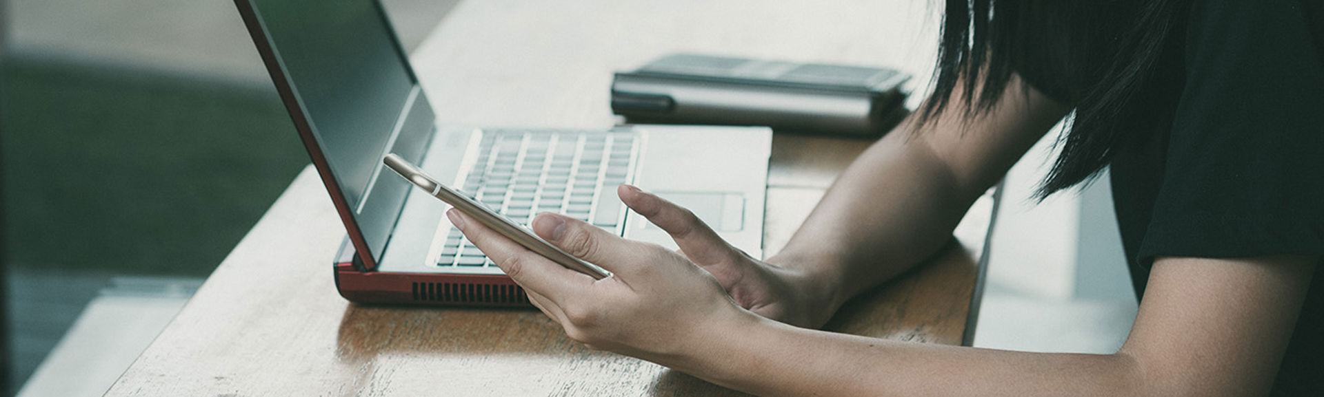 A person at a desk using a laptop and mobile phone
