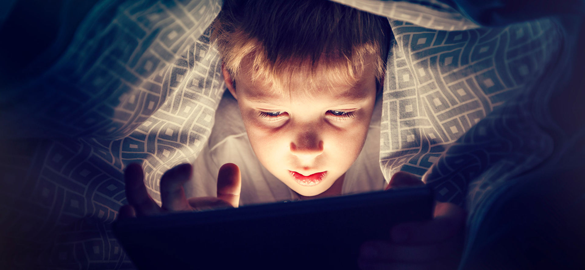 Boy watching video on tablet in bed