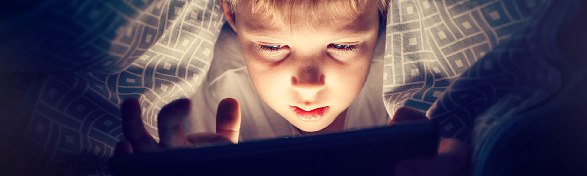 Boy watching video on tablet in bed