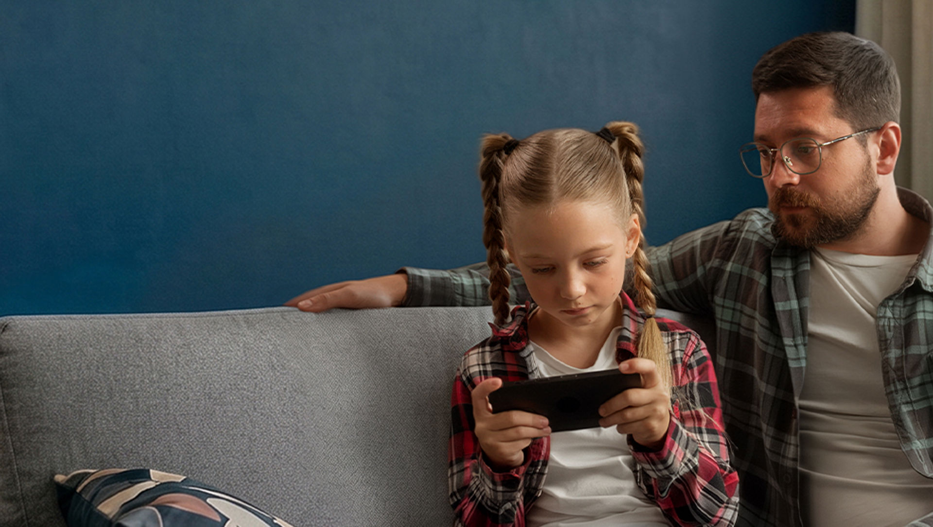 Father watching daughter using a tablet
