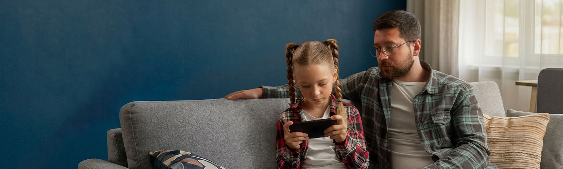 Father watching daughter using a tablet