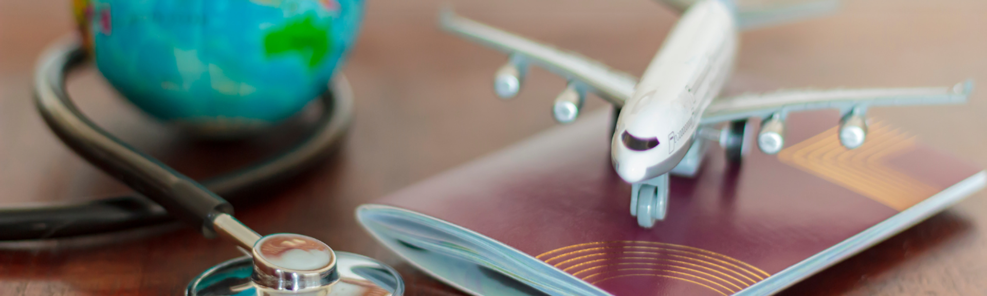 A toy plane sitting on a passport, both sitting on a desk