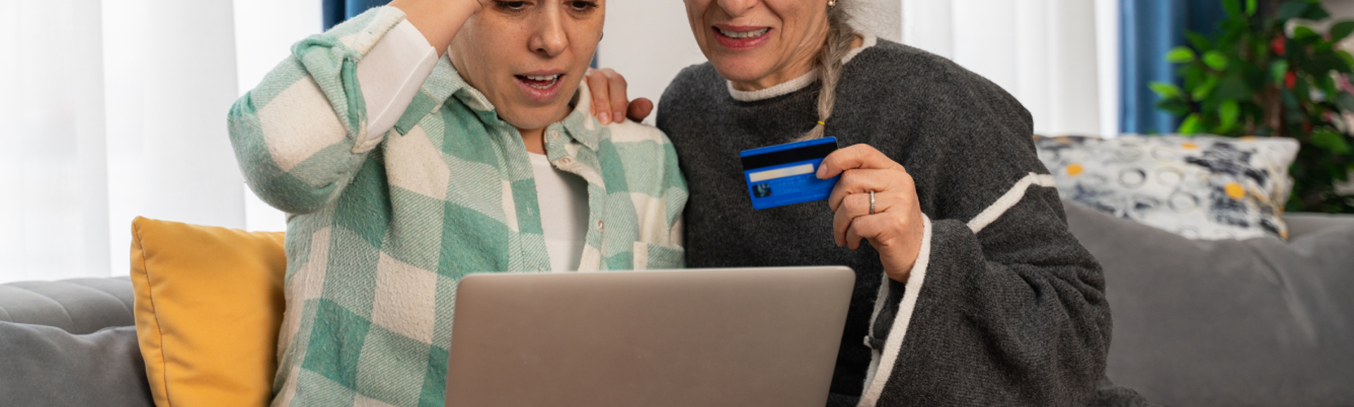 Two distressed women using a laptop with a credit card in hand