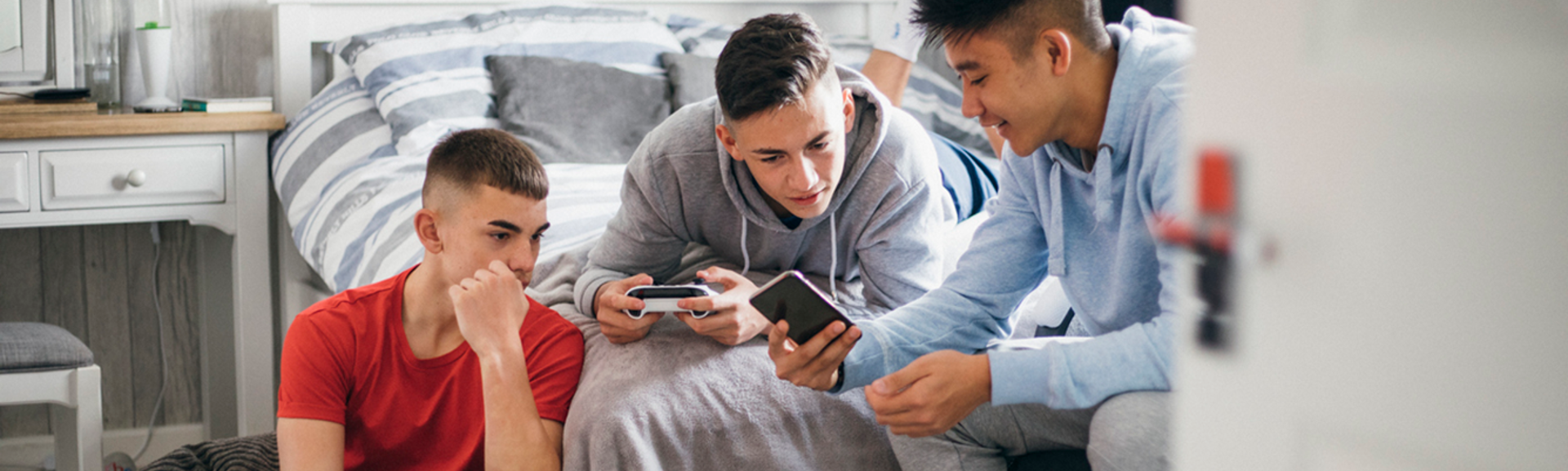 Teenage boys looking at phone while gaming