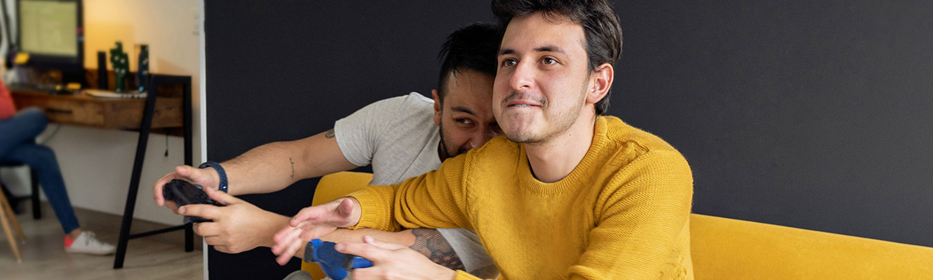 Two young men playing computer games while sitting on a couch