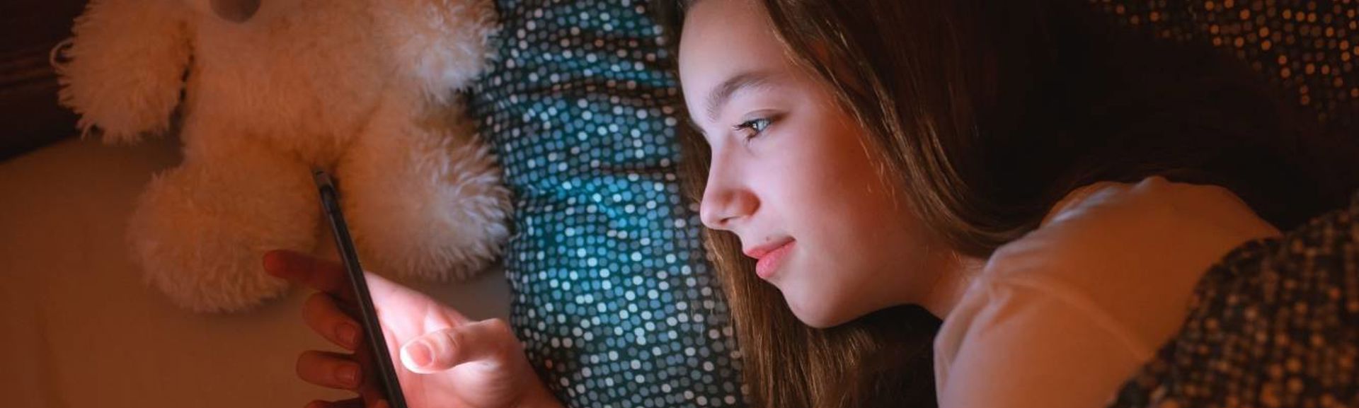 Young girl using mobile phone in bed at night