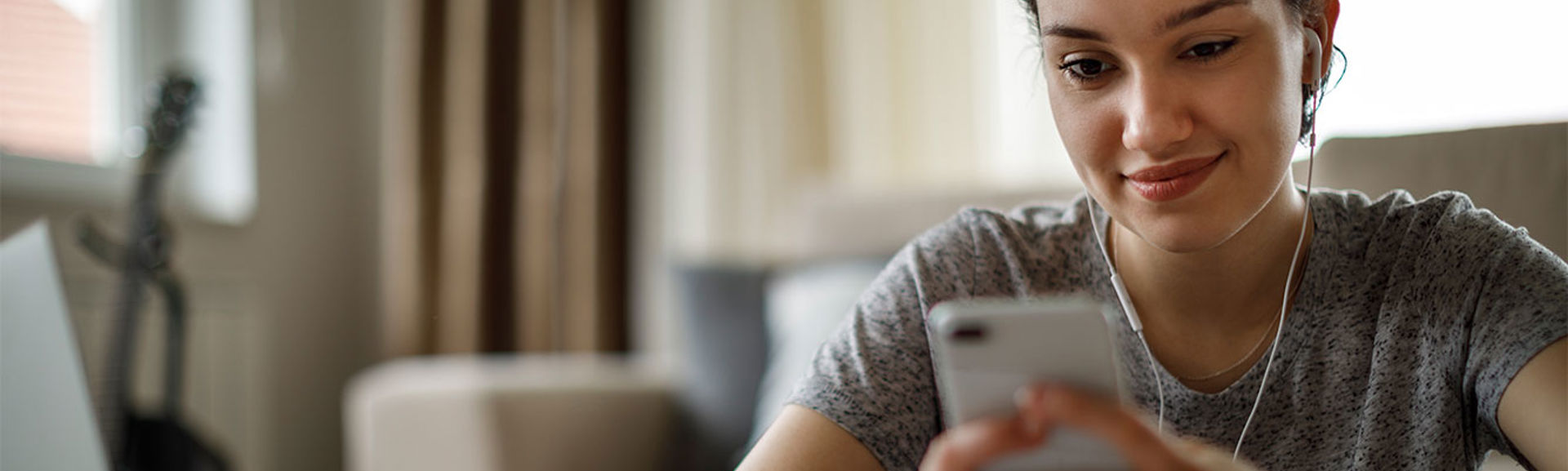 Woman wearing headphones smiling at her mobile phone