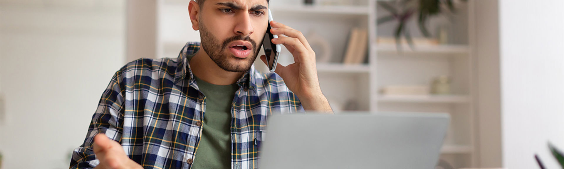 Unhappy man on his phone while using a laptop