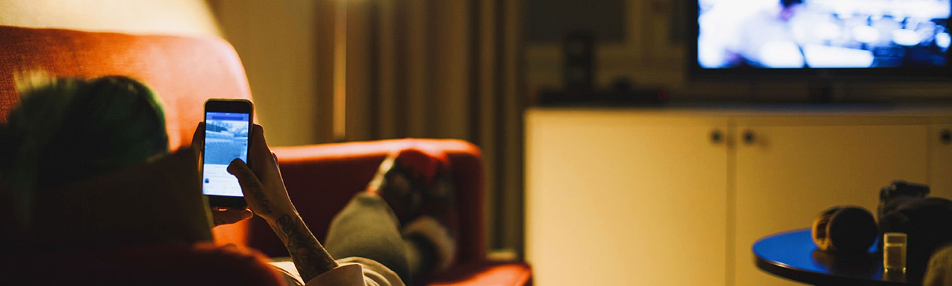 Person reading something on their phone while lying on the sofa