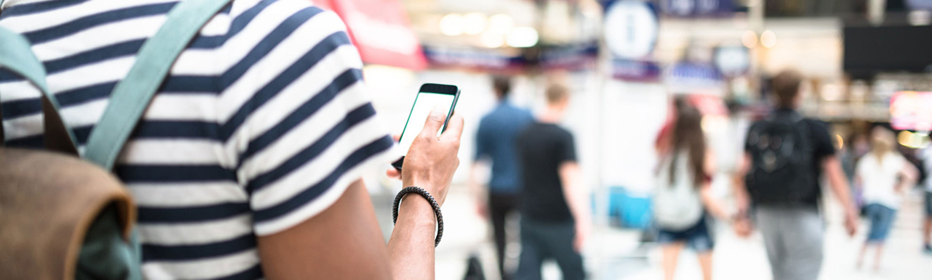 A person using a mobile phone as they walk through a train station
