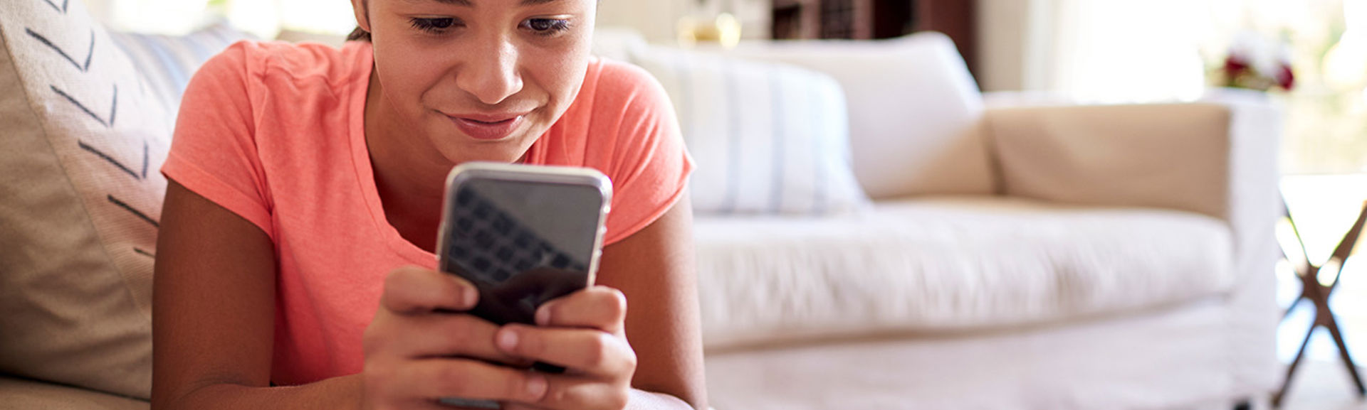 Teenage girl using smartphone on sofa