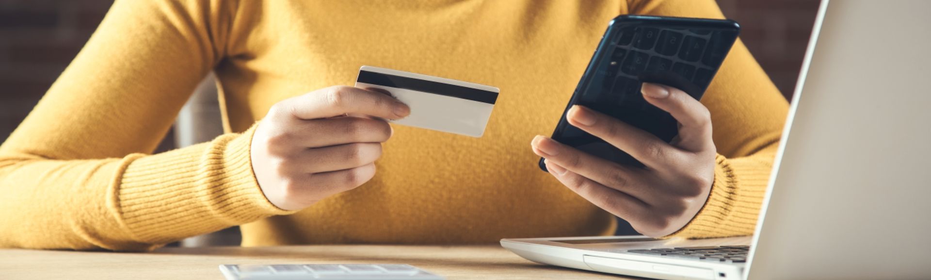 A person using a card to pay for something via their phone or laptop