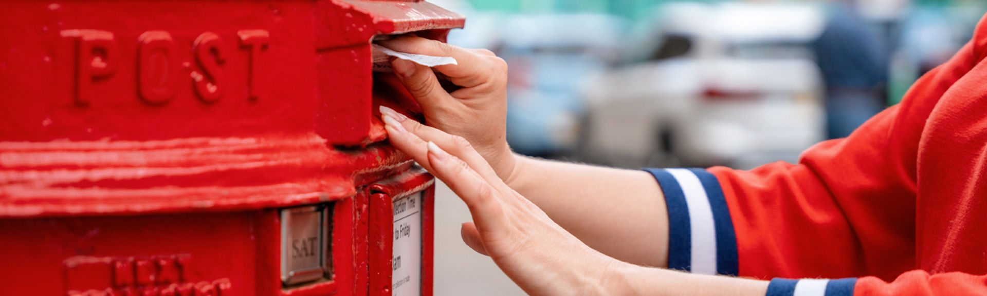 Woman in red jumper posting a letter