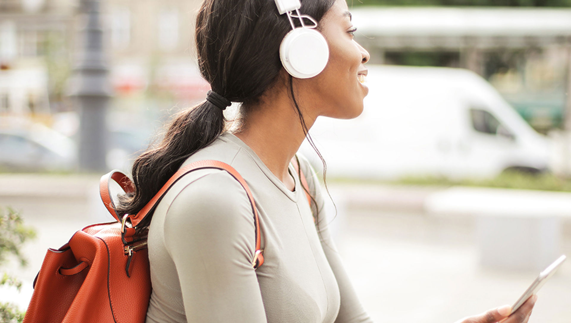 Young woman outdoors listening to a podcast on her smartphone