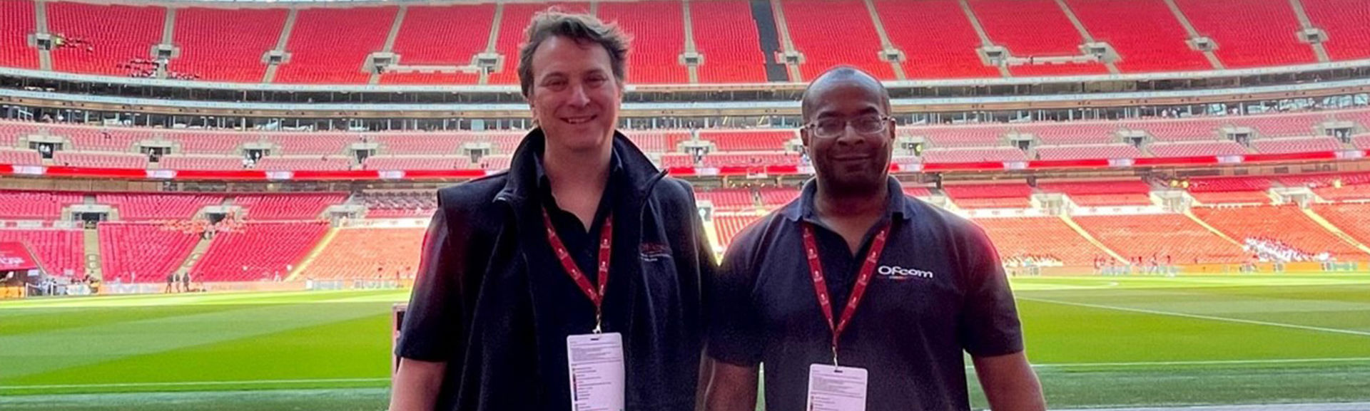 Two Ofcom colleagues standing in a football stadium