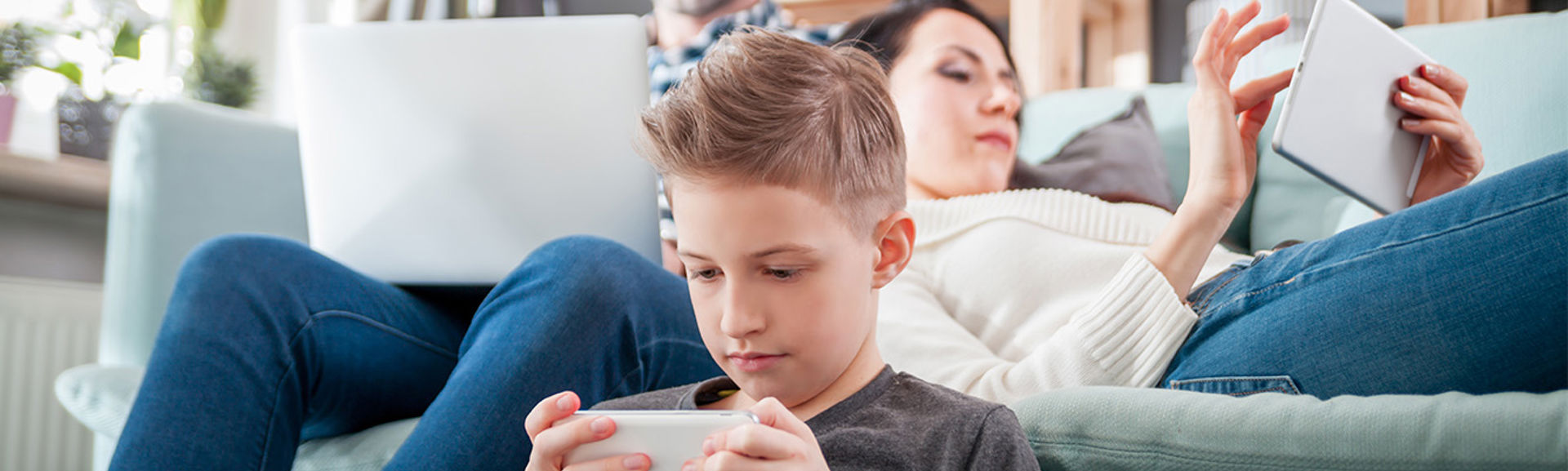 Family relaxing on the sofa with their respective devices.