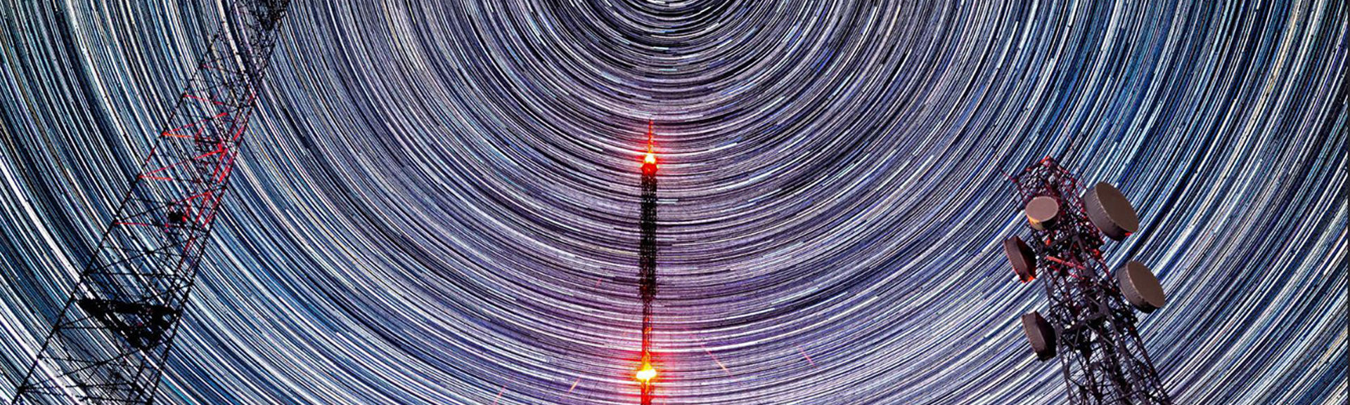 Timelapse shot of telecoms masts with stars travelling behind them in the night sky