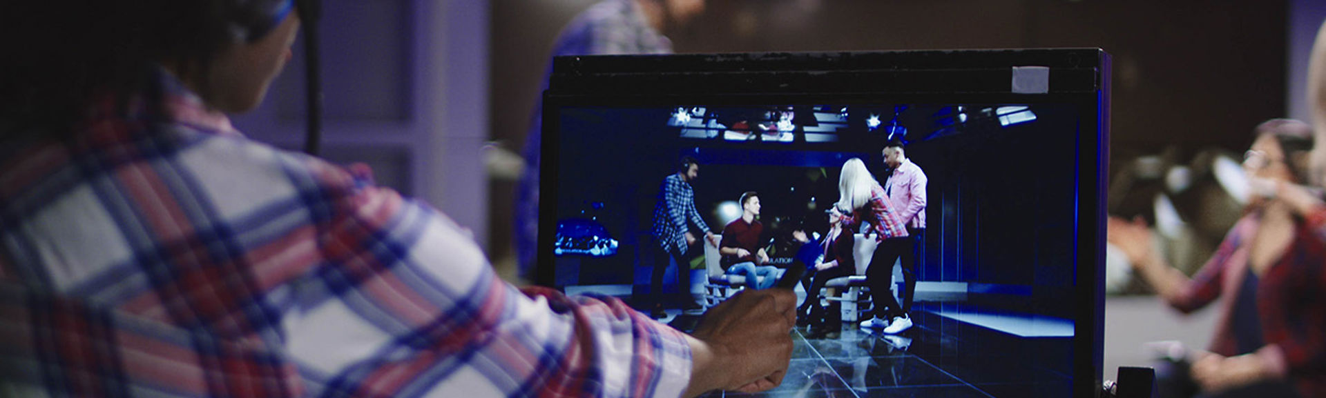 Crew pointing to a video screen on the set of a TV production