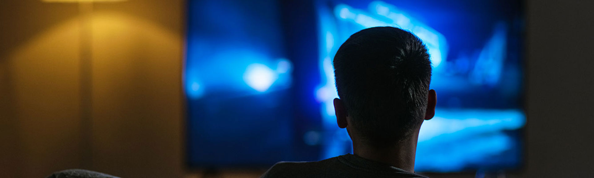 A man sitting on a sofa watching television