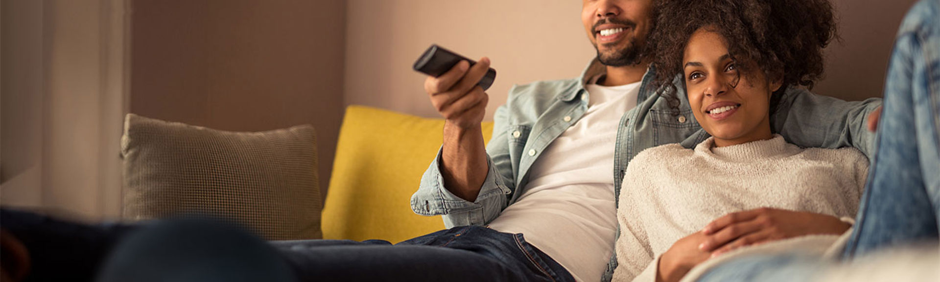 Couple on couch watching TV with a smart speaker in the foreground