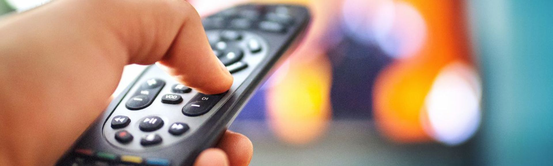 A person pointing a remote control at a television screen