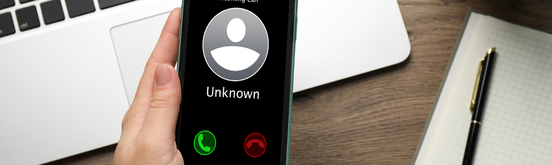 A person holding a mobile phone with an 'Unknown Caller' on screen