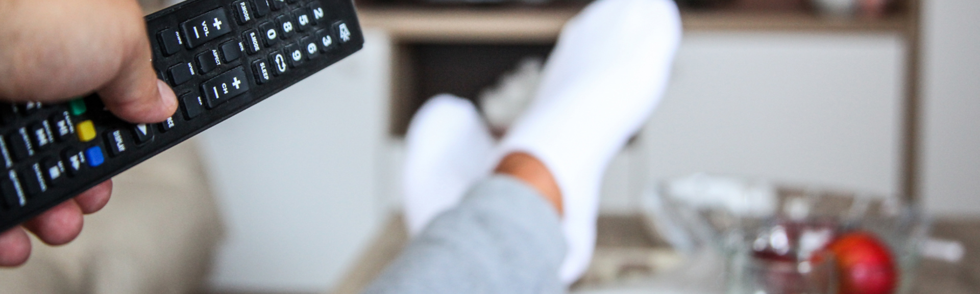 A person pointing a remote control at a television screen