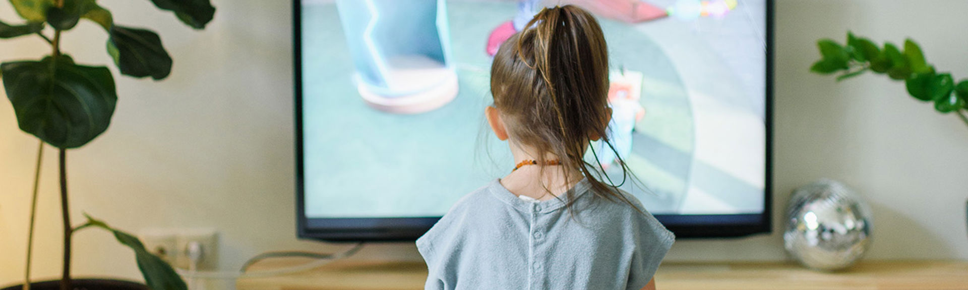 Young girl sitting in front of a television set.