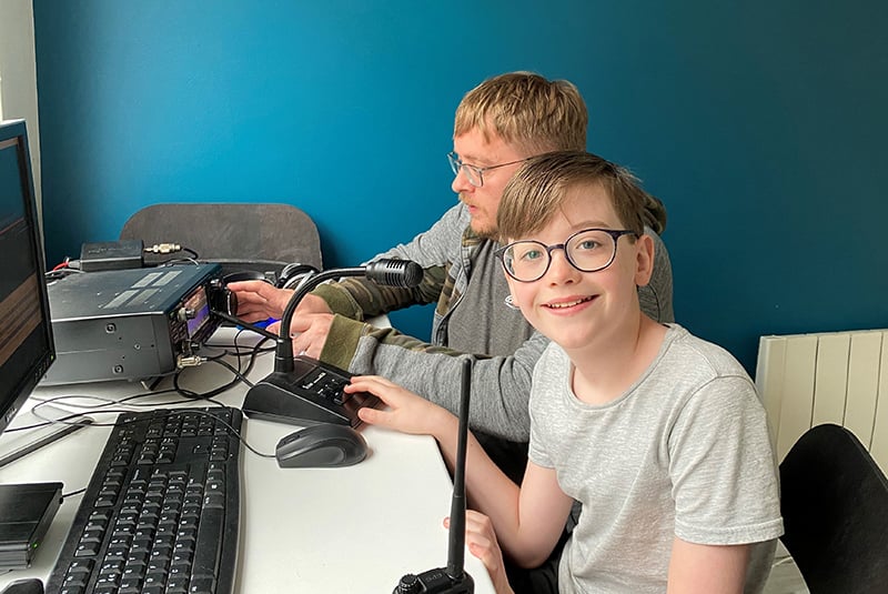 William smiles for the camera as he and his dad Michael use their amateur radio equipment and computer together.