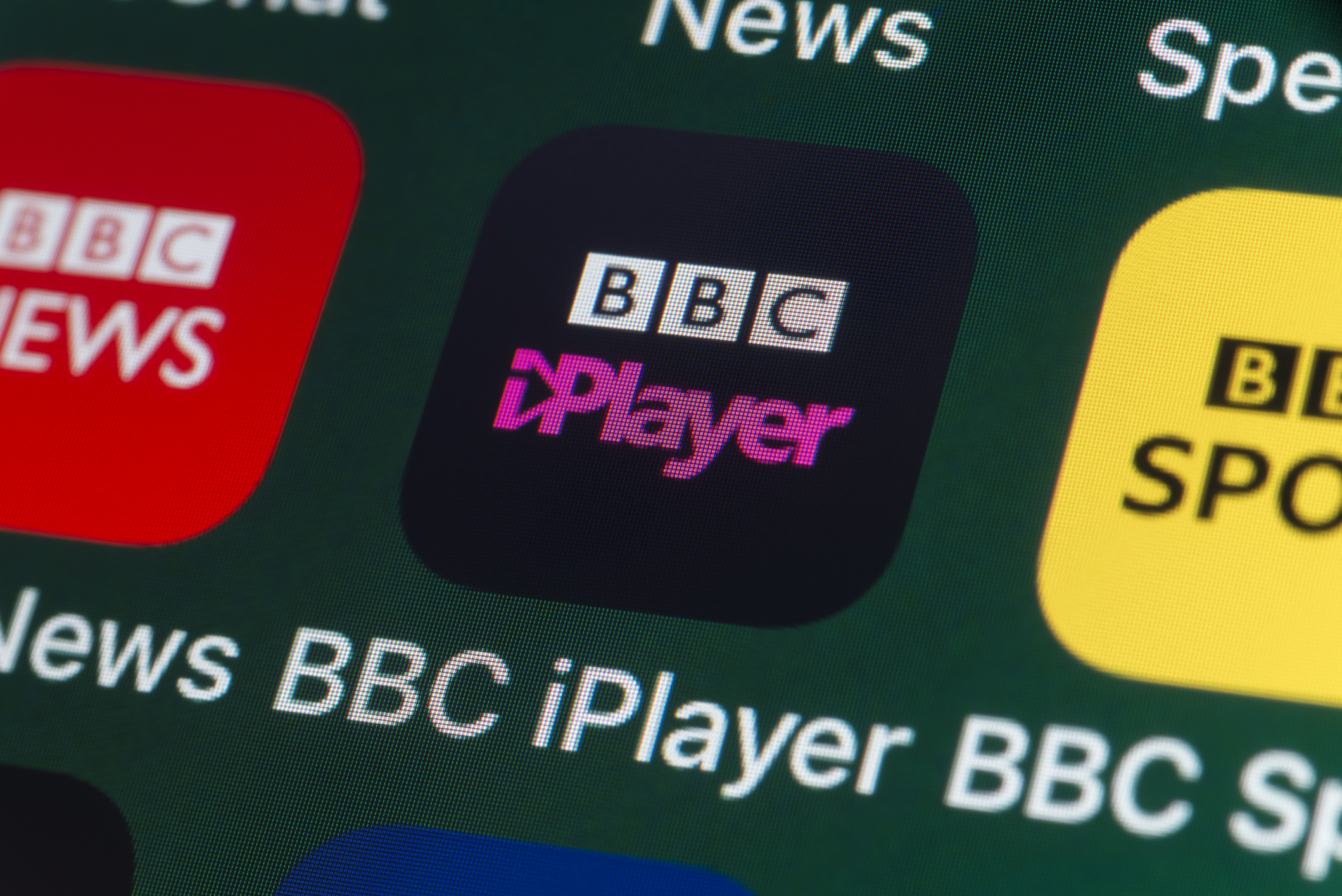 The buttons of the BBC iPlayer app, surrounded by BBC News, BBC Sport, News and other apps on the screen of an iPhone