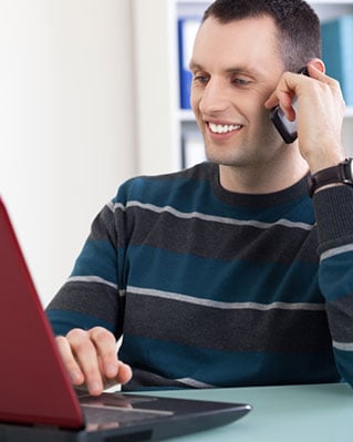 Man on phone looking at laptop