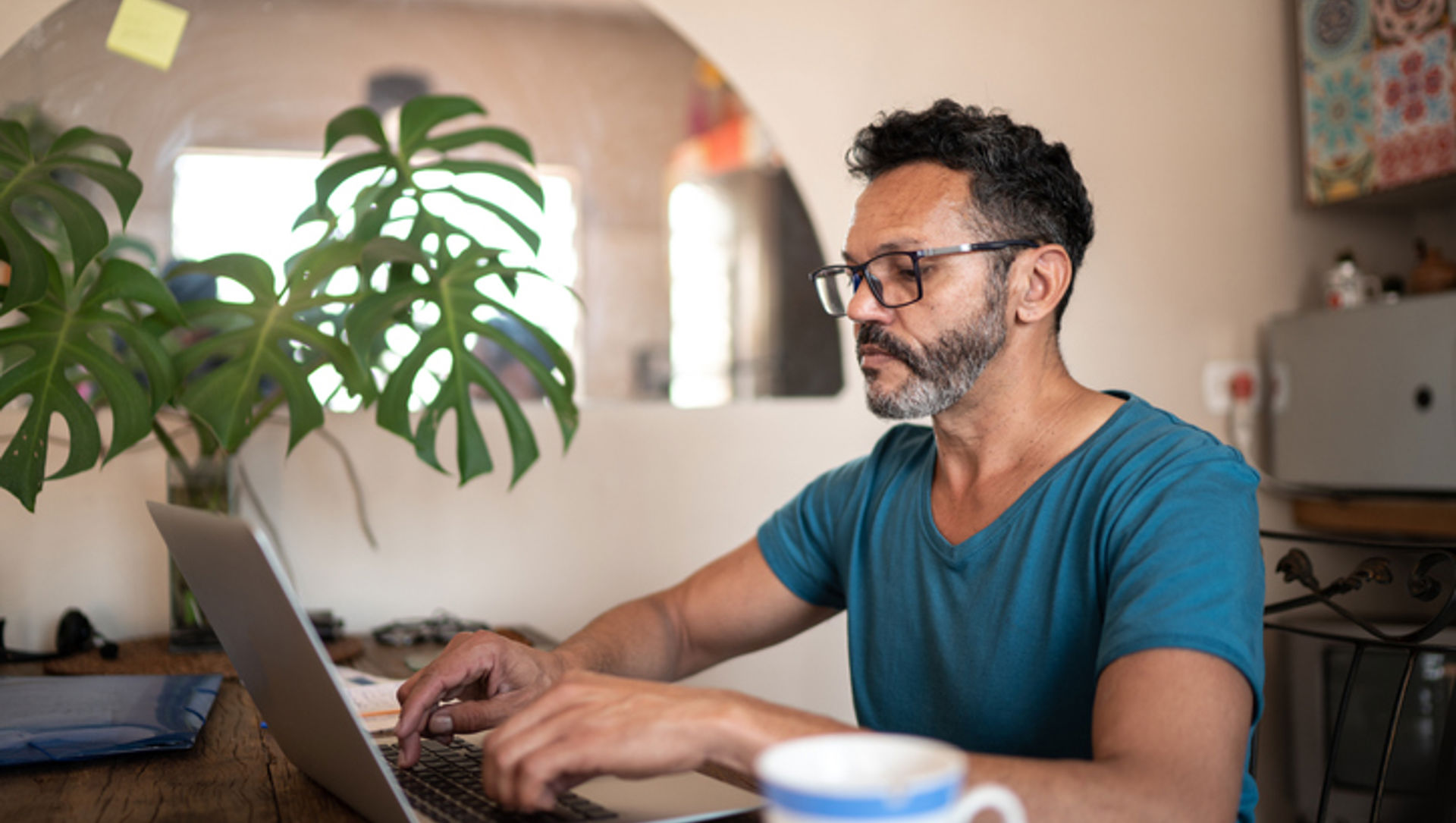 Middle aged man using his laptop in his kitchen