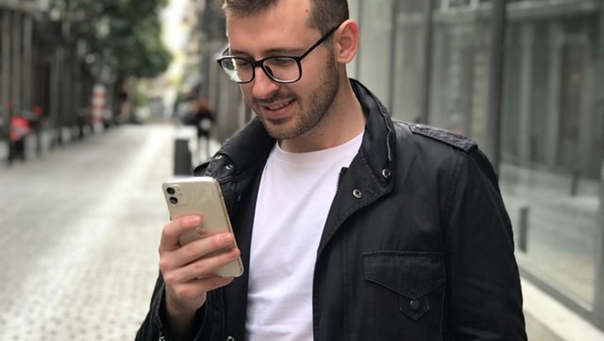 man looking at his phone and smiling in a city