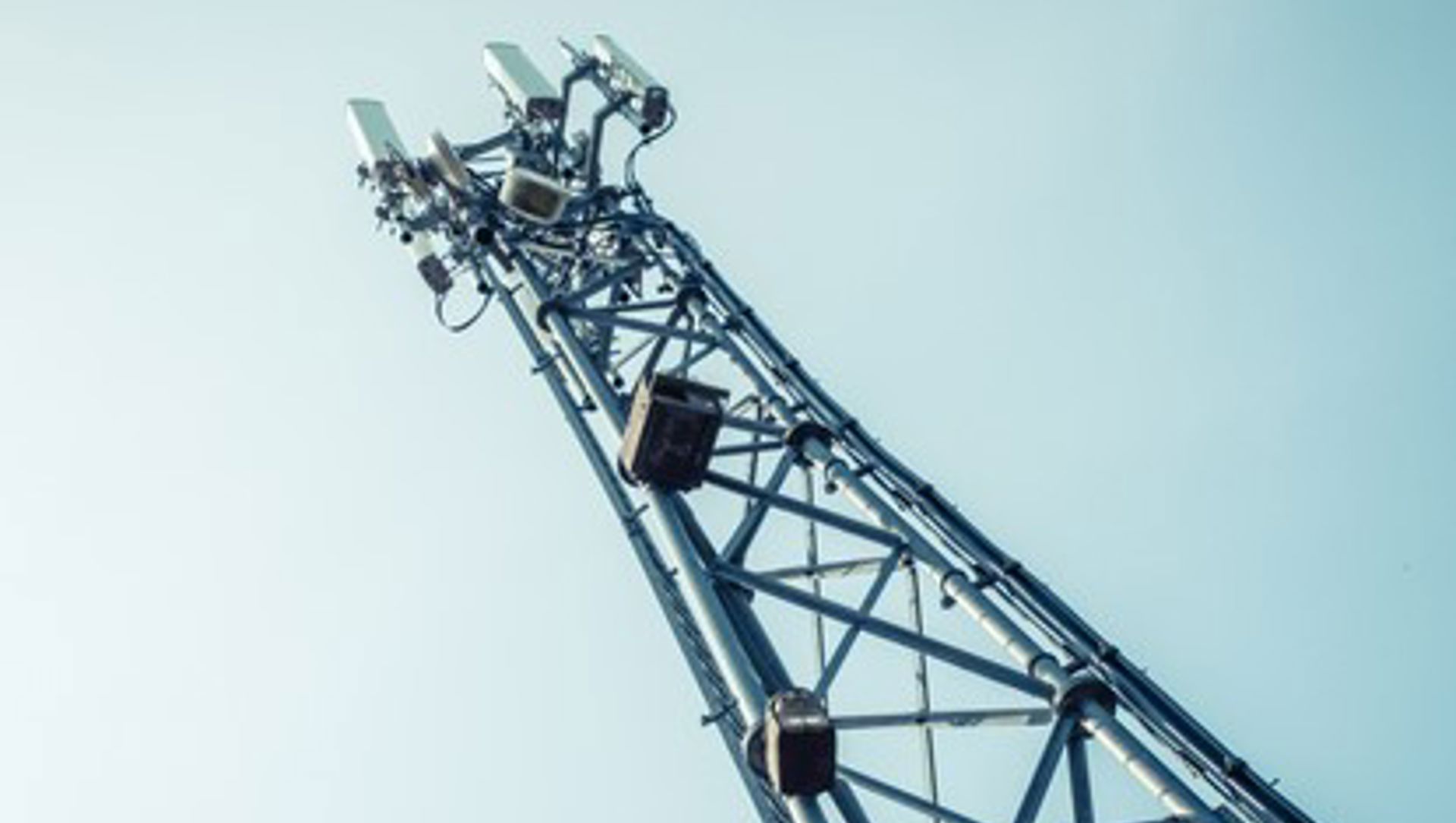 Angled view of a telcoms mast from below against a clear blue sky